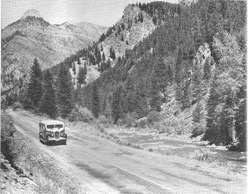 Yellowstone-bound, a Park motor coach starts up the Gallatin Valley with Castle Rock in the background. The comfortable buses have roll-back tops that permit full views of the surrounding rocky walls.